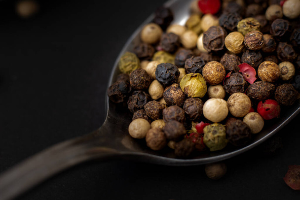 black and white pepper in a wooden bowl on a dark background. - Foto, imagen