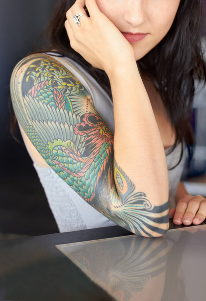 De schoonheid zit in het detail. Gesneden schot van een jonge tatoeëerder pronken met haar half-mouw tatoeage. - Foto, afbeelding