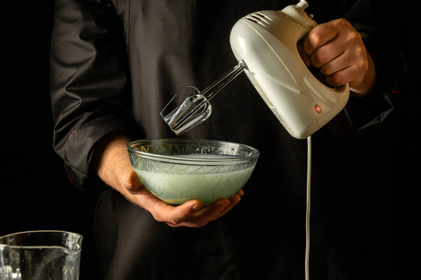 Fazendo um milkshake com um misturador elétrico de mão. Bebida refrescante pelas mãos do chef. - Foto, Imagem
