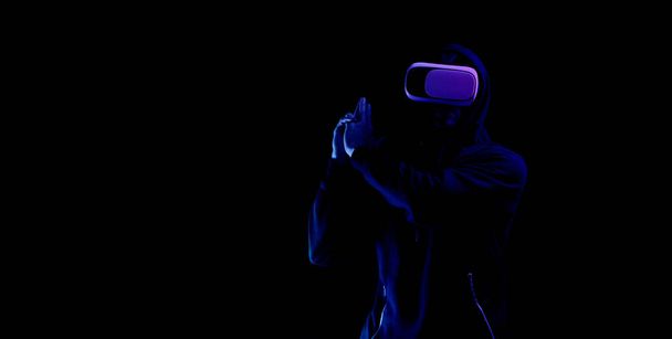 Juego de realidad virtual vr. Joven hombre en gafas digitales para tecnología de realidad virtual aislado sobre fondo de neón oscuro. Estudio y mundo virtual en simulación 3D - Foto, imagen