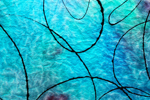 Cristal azul antiguo con pintura negra salpicado en la superficie y la luz que brilla a través de la parte posterior del vidrio - Foto, Imagen