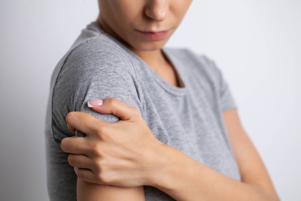 Болі в руці жінка, яка страждає від притулку болю на сірому фоні
 - Фото, зображення