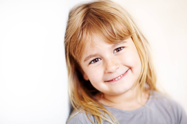 Έχει τόσο γλυκό χαμόγελο. Ένα χαριτωμένο μικρό ξανθό κορίτσι χαμογελά στην κάμερα - copyspace. - Φωτογραφία, εικόνα