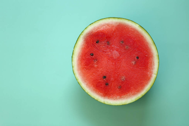 Watermelon in a cut on a green background. Watermelon pulp close-up. ripe red watermelon half - Fotó, kép