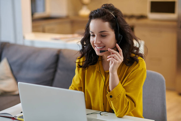 Cute young woman in a mustard shirt sitting at the laptop - Фото, зображення