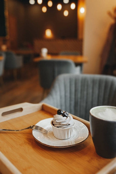 大気中のカフェのテーブルの上に新鮮なベリーとクリームとカップケーキ。選択的焦点垂直方向に - 写真・画像