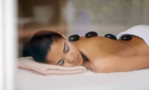 Uma de alegrias pequenas de vidas. Tiro de uma jovem mulher desfrutando de um tratamento de rocha quente em um spa. - Foto, Imagem