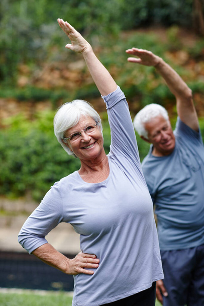 Estiramiento hacia la salud y la felicidad. Toma de una pareja mayor haciendo yoga juntos al aire libre. - Foto, imagen