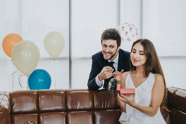 Young couple celebrating new year together, boyfriend gives a present to girlfriend. - Photo, Image
