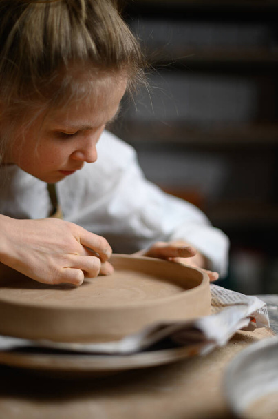 Meisje maken klei plaat in keramische werkplaats - Foto, afbeelding