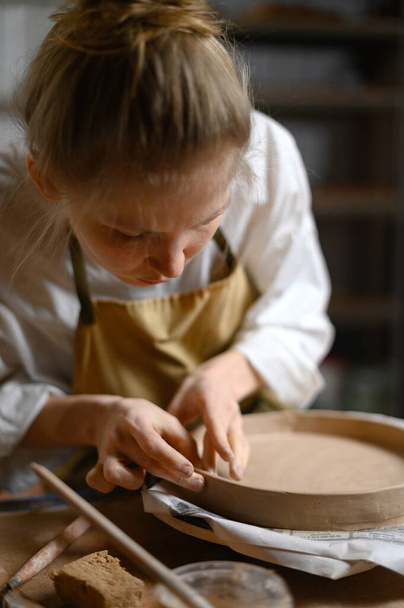 Chica hacer plato de arcilla en taller de cerámica - Foto, imagen