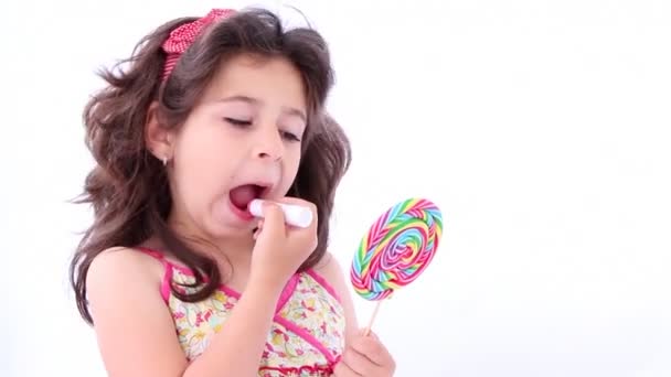 Маленька дівчинка одягає помаду, використовуючи льодяник як дзеркало
 - Кадри, відео