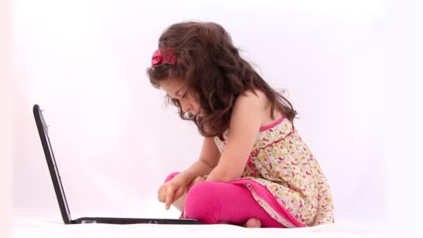 Linda chica jugando con un ordenador portátil, tableta contra fondo blanco
 - Metraje, vídeo