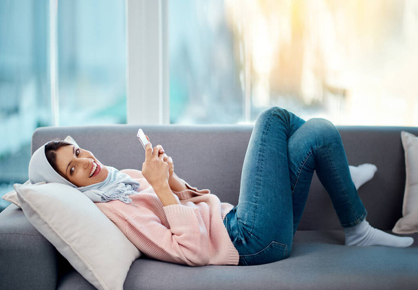 Ligado do conforto do meu sofá. Retrato de ângulo alto de uma jovem atraente enviando um texto enquanto relaxa em seu sofá em casa. - Foto, Imagem