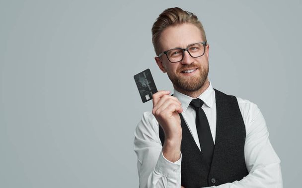 Smiling businessman with plastic card in studio - Foto, afbeelding