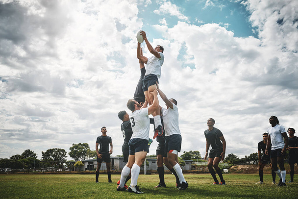 Reik naar de hemel. Shot van twee rugby teams concurreren over een bal tijdens een lijn uit een rugby wedstrijd buiten op een ingediend. - Foto, afbeelding