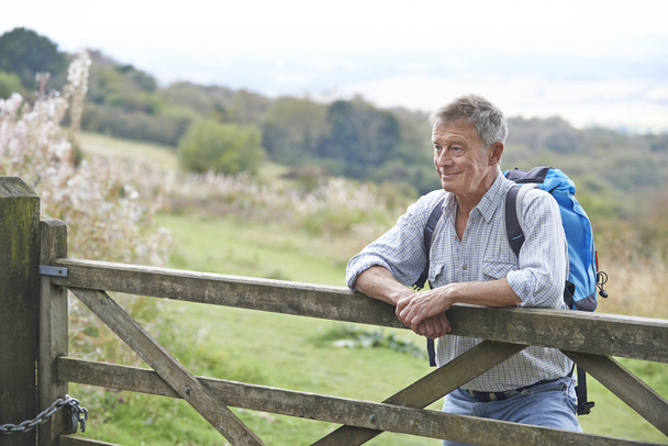 Senior Man Hiking In Countryside Resting By Gate - Foto, Bild