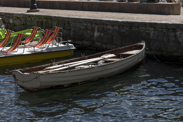 Wooden rowing boat moored in the harbor of Riva del Garda on Lake Garda - Photo, Image