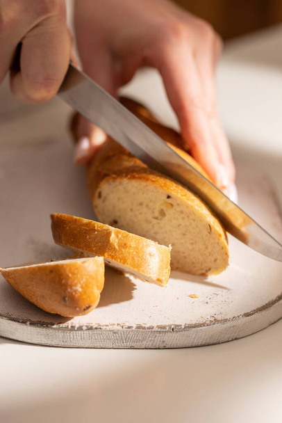 Woman cuts freshly baked bread - Fotó, kép