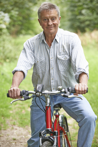 Senior man genieten van fietstocht op het platteland - Foto, afbeelding
