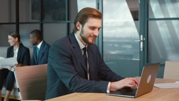 Ofisinde dizüstü bilgisayarı olan takım elbiseli, gülümseyen bir adam. - Video, Çekim