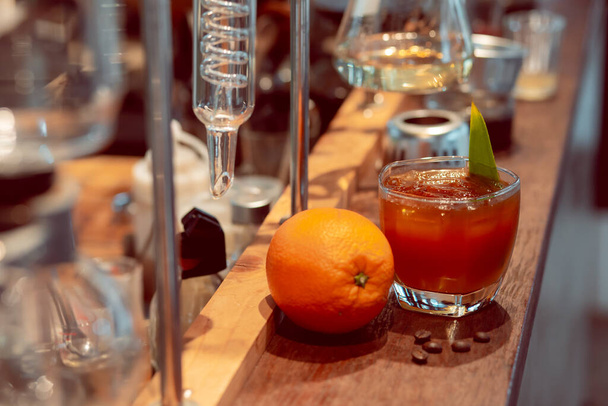 Крупним планом кава змішана з апельсиновим соком в прозорому келиху Поміщена поруч з великим апельсином в лабораторії
 - Фото, зображення