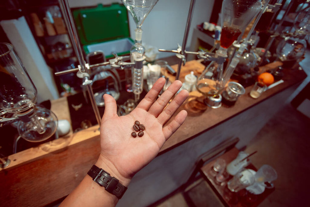 Kávébab egy laborkutató kezén, az italgyártásban használt kávébab minőségének vizsgálatához.. - Fotó, kép