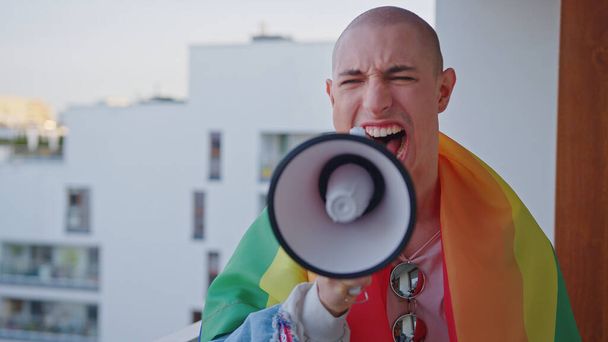 μη δυαδικό queer πρόσωπο ουρλιάζοντας σε ager και αγωνίζονται για τα δικαιώματά τους με σημαία ουράνιο τόξο στους ώμους - Φωτογραφία, εικόνα