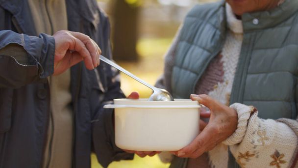 Wohltätigkeitsorganisation verschenkt Lebensmittel in weißen Kochschoten, um Menschen in Not zu helfen. - Foto, Bild