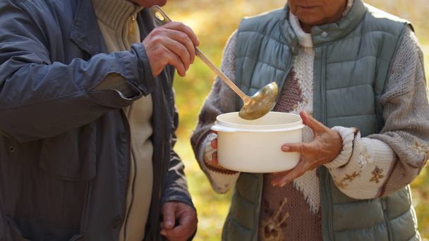 Twee Kaukasische mensen die soep met elkaar delen. Het concept van hulpbehoevenden helpen. - Foto, afbeelding