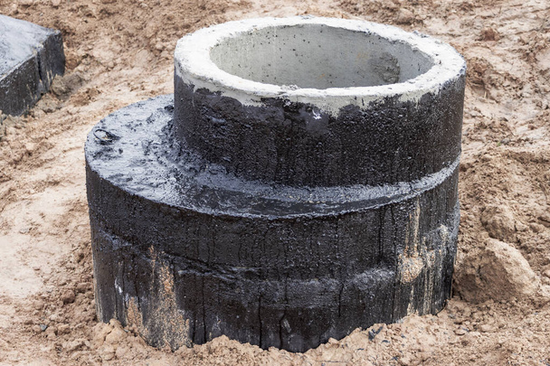 Монтаж железобетонной скважины для водоснабжения и канализации на строительной площадке. Кольца с чугунным люком и строительным инструментом - Фото, изображение