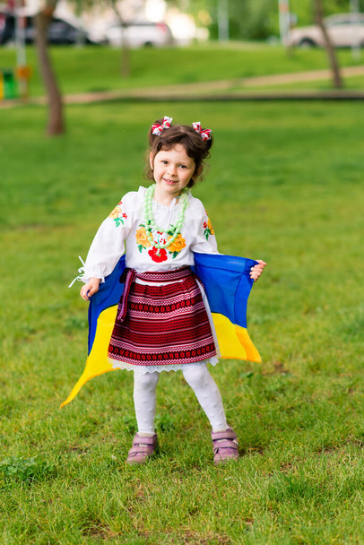 Girl with the flag of Ukraine. She is dressed in an embroidered shirt and a wreath on her head - Ukrainian national dress. - Photo, image