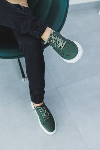 Male legs close-up in black trousers and green leather lace-up shoes. Men's shoes for spring and summer - Photo, Image