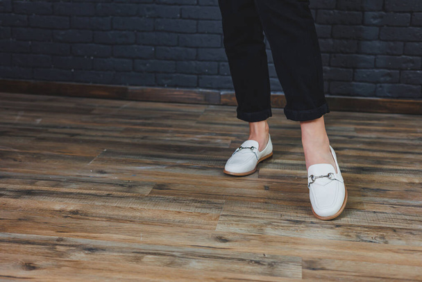 Gambe femminili in primo piano in pantaloni neri e mocassini beige in pelle. Nuova collezione primavera-estate di scarpe in pelle da donna 2022 - Foto, immagini