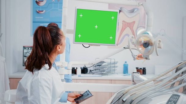 Zahnarzt blickt auf Monitor mit horizontalem grünen Bildschirm - Foto, Bild