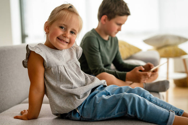 Kislány és fiú néz videó vagy játék a digitális eszköz táblagép, okostelefon. A gyermekek digitális függőségének fogalma. - Fotó, kép