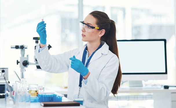 А вот и он. Обрезанный снимок сфокусированной молодой женщины-ученого, смешивающей химикаты в лаборатории в течение дня. - Фото, изображение