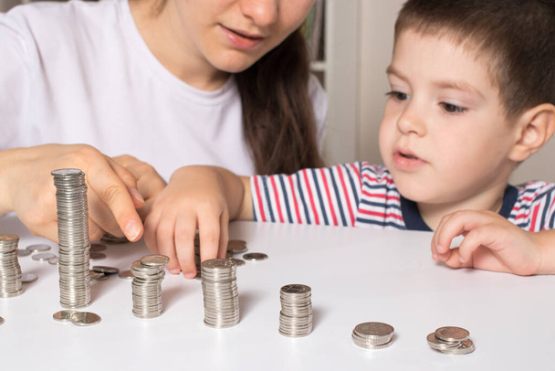 A szülő megtanítja a gyermeknek, hogyan kezelje a pénzt. Pénzügyi ismeretterjesztő kurzus óvodáskorú és iskoláskorú gyermekek számára. - Fotó, kép