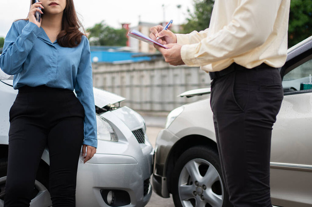 Azjatki kierowca Porozmawiaj z agentem ubezpieczeniowym do badania uszkodzonego samochodu i sprawdzania klienta na formularzu wniosku o zgłoszenie po wypadku. Pojęcie ubezpieczenia i wypadków drogowych. - Zdjęcie, obraz