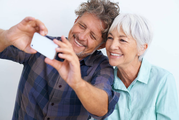 Esa es buena. Foto de una feliz pareja de ancianos mirando un teléfono celular. - Foto, imagen