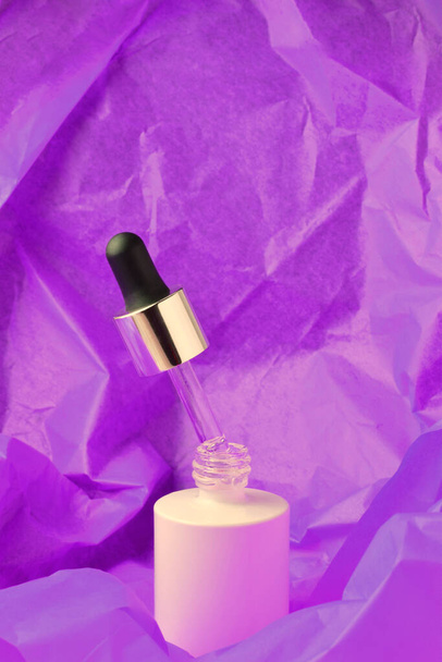 Druppel cosmetische container op violette achtergrond. - Foto, afbeelding