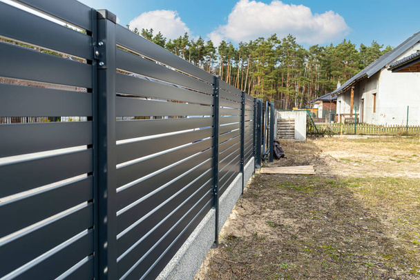 Modern antracit panel kerítés, látható ívek és kerítés alapítvány csatlakozó, kilátás a kertből. - Fotó, kép