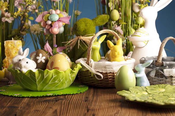 Великодній час. Великодні прикраси на сільському дерев'яному столі. Великодній кролик, великодні яйця в кошику та капустяному листі. Букети з весняних квітів
.  - Фото, зображення