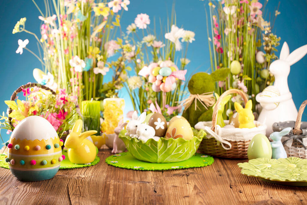 Pâques. Décorations de Pâques sur la table rustique en bois. Lapin de Pâques, œufs de Pâques dans le panier et feuille de chou. Bouquets de fleurs de printemps.  - Photo, image