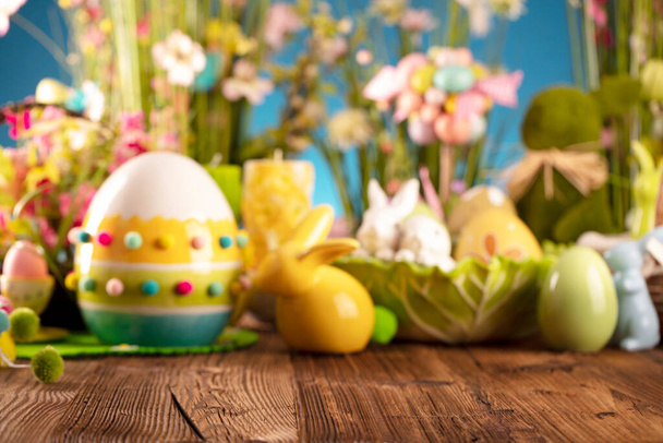 Великодній час. Великодні прикраси на сільському дерев'яному столі. Великодній кролик, великодні яйця в кошику та капустяному листі. Букети з весняних квітів
.  - Фото, зображення
