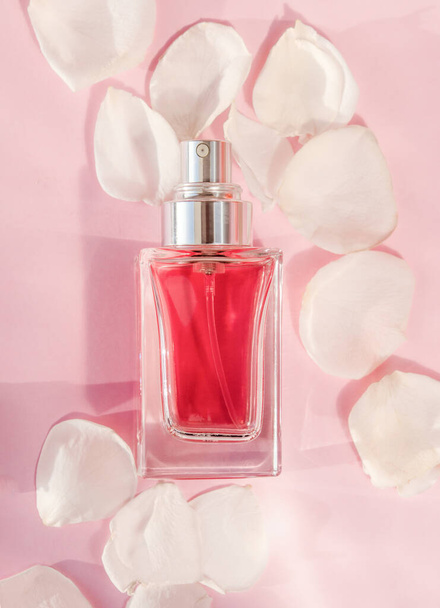 Transparentní parfém láhev ležící na růžovém pozadí s okvětními lístky růží - Fotografie, Obrázek