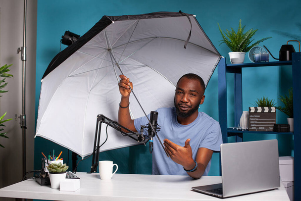 Technology reviewer testing flash reflector umbrella presenting size and benefits - Photo, Image