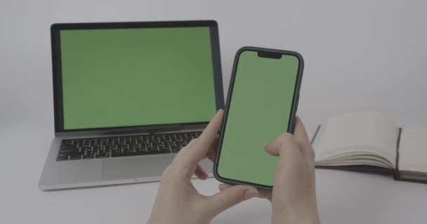 Chroma Key Mock-Up op Smartphone en laptop. Vrouwelijke handen met behulp van telefoon met groen scherm - Video