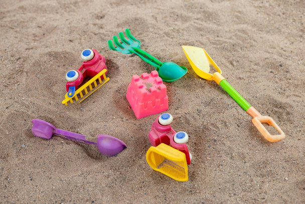 selective focus colorful children's toys on the sand Toy car and toy shovel concept in the technology age Children only play mobile phone games. They don't play with toys like before. - Fotografie, Obrázek