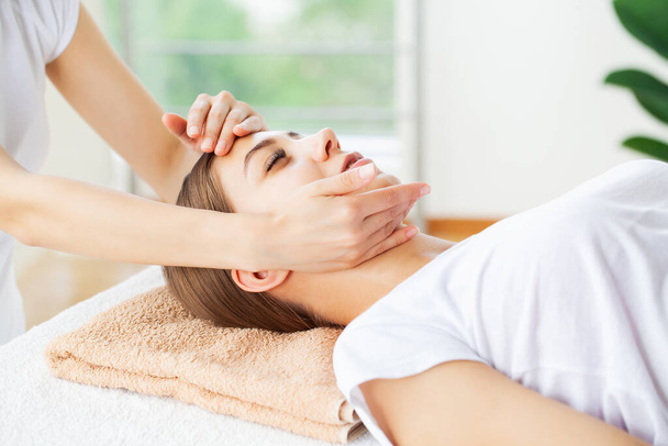 Młoda kobieta korzystających z masażu twarzy w salonie spa - Zdjęcie, obraz